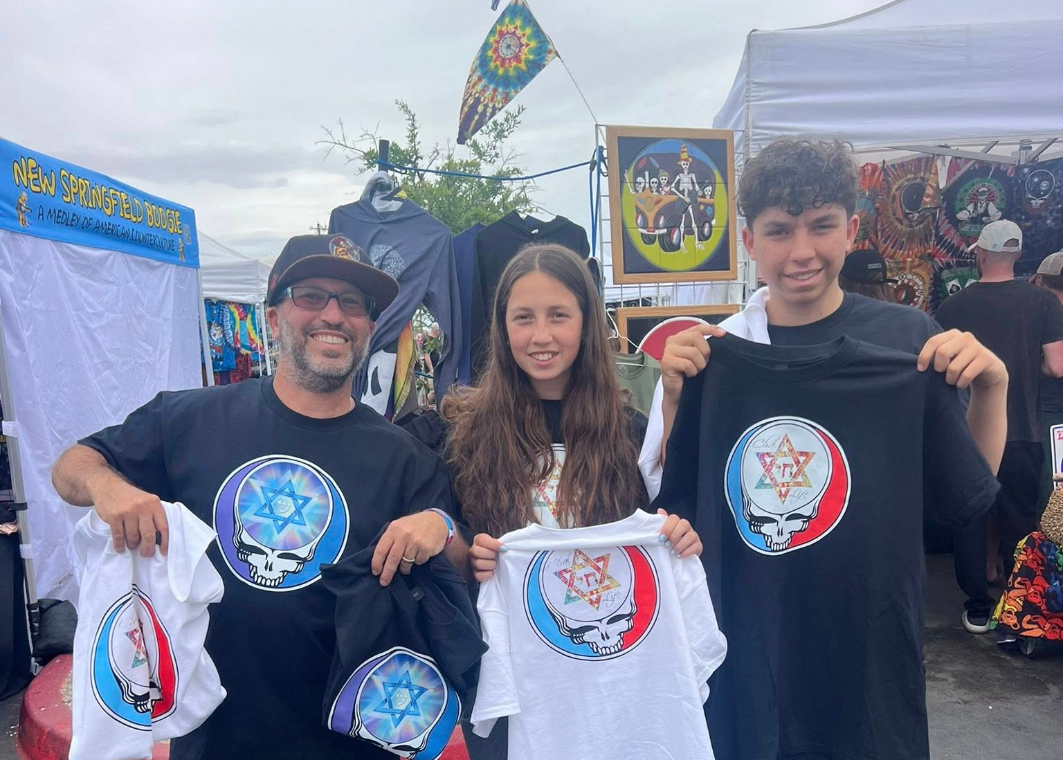 Gadi and his children holding Lion of Zion T-Shirts at an outdoor event